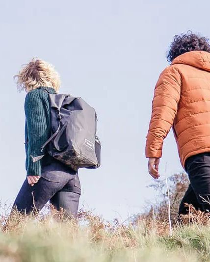 two people walking through hillside wearing finisterre x reskinned clothing