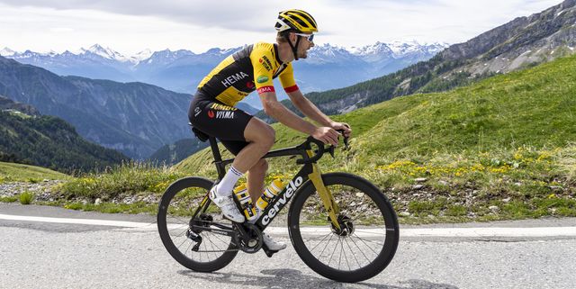 wielrenner die in zwart gele fietskleding een berg op fietst