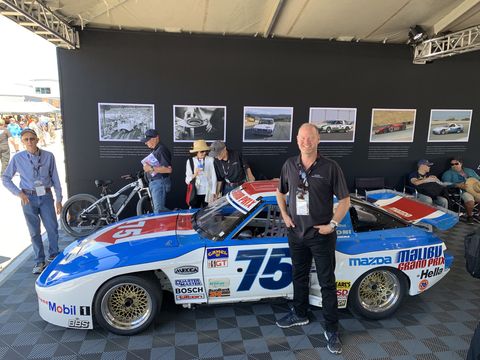 tommy kendall stands in front of his mazda rx 7 race car