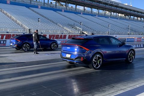 two blue kia ev6s parked on the starting line of a drag strip
