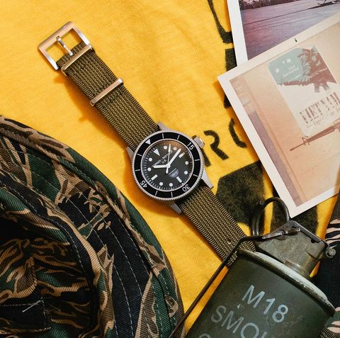 flat lay of a watch surrounded by camouflage and military equipment