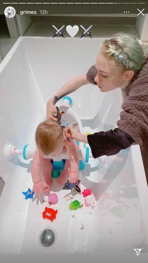 grimes standing over a tub while cutting her son's hair