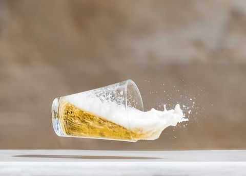 Impact of a glass  with beer that falls down on the soil.