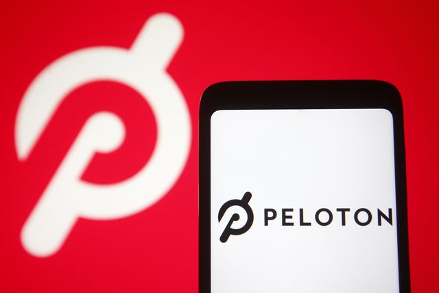 in this photo illustration a peloton logo is seen on a smartphone and a pc screen