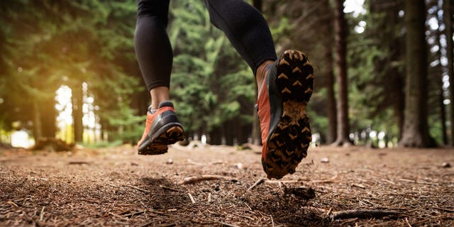 in winter running sports shoe, woman running in the forest