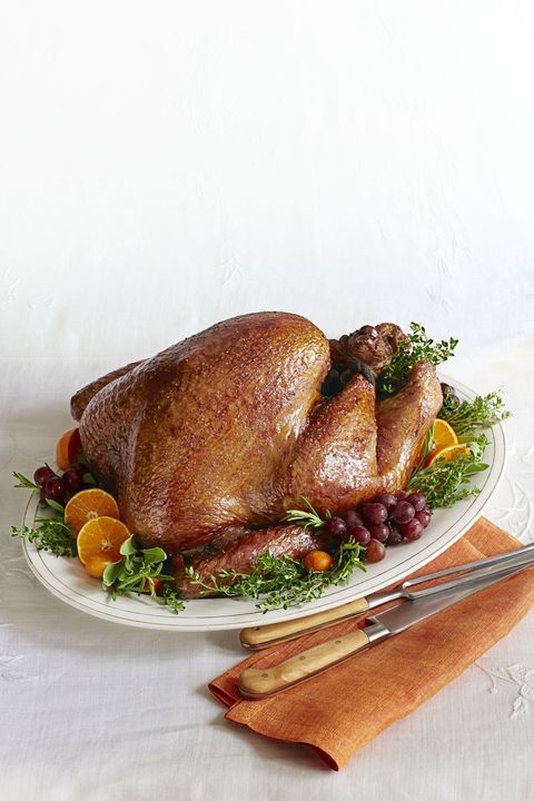golden roasted turkey on a serving platter with grapes, orange slices, and herbs