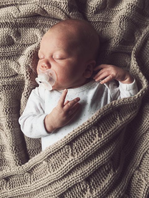 un bebé recién nacido, con chupete, duerme plácidamente