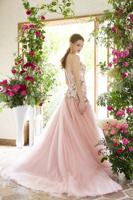 優しいピンクの花のモチーフが施されたピンクドレスを着たモデル。