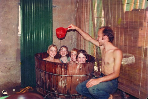 a man washes several children in a barrel