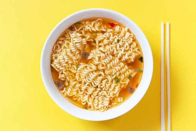 instant noodle soup in a white bowl on yellow background top view