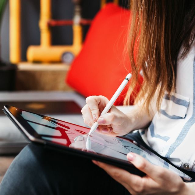 woman sitting in modern living room using apple pencil to draw on ipad