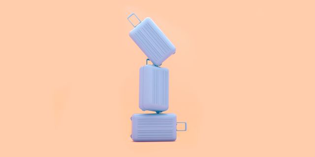 suitcases piled up on a peach background