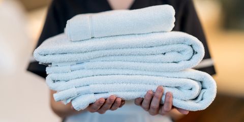 close up of unrecognizable housekeeper holding towels at a hotel