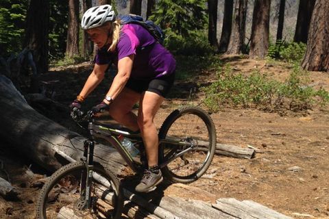 mujer montando bicicleta de montaña sobre troncos