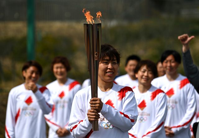 un relevista japonés sostiene la antorcha olímpica en el inicio del relevo hacia tokio en fukushima