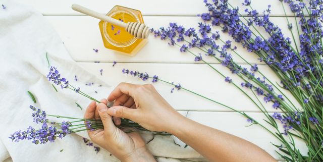 jar of honey with honey dripper and woman's hands with lavender flowers