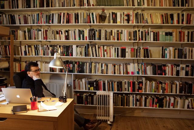 el escritor javier cercas, sentado en su despacho rodeado de cientos de libros