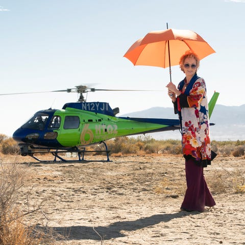 jean smart with a parasol about to board a helicopter