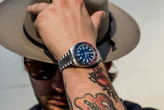man taking off a hat while wearing a watch on his wrist