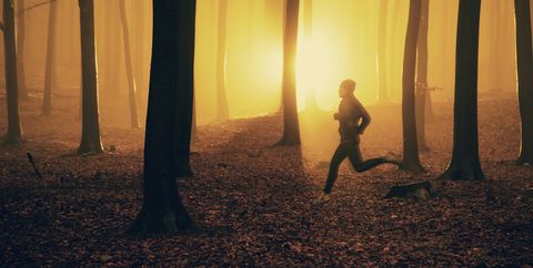 Jogger at sunrise in misty forest