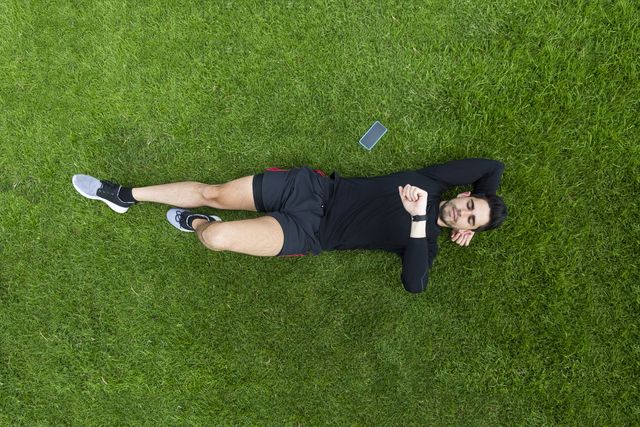 jogger lying in grass looking on watch