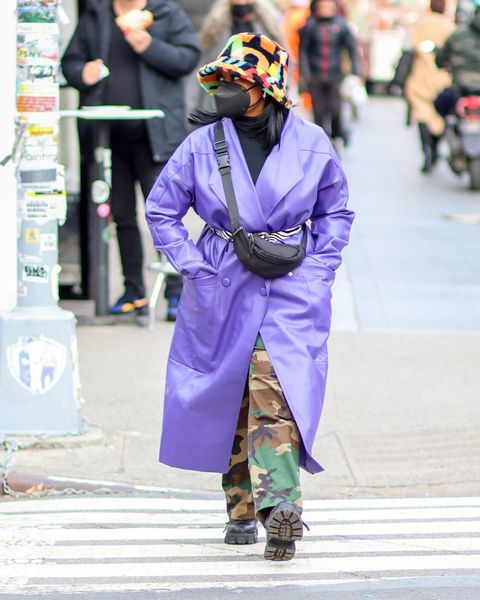 a woman wearing a purple coat, camouflage pants and a face mask