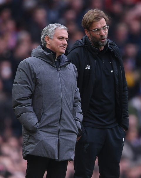 premier league coaches jose mourinho and jurgen klopp talk to each other, as they watch their teams from the side of the field