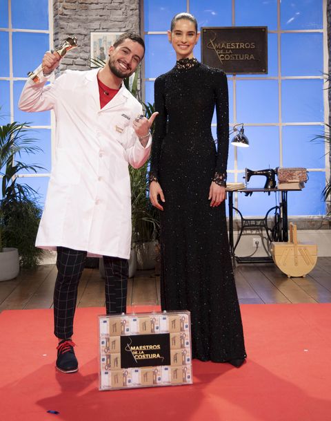 Joshua Vázquez posa con los premios de 'Maestros de la Costura 3' y con la modelo que luce su vestido.