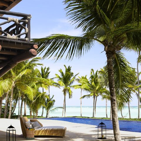 outdoor platform by the beach with a lounge and surrounded by grass and palm trees