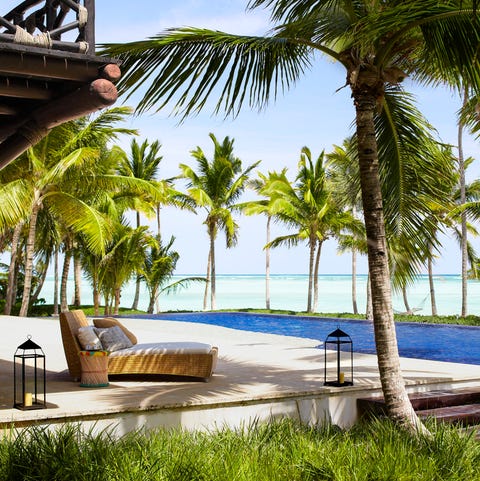 outdoor platform by the beach with a lounge and surrounded by grass and palm trees