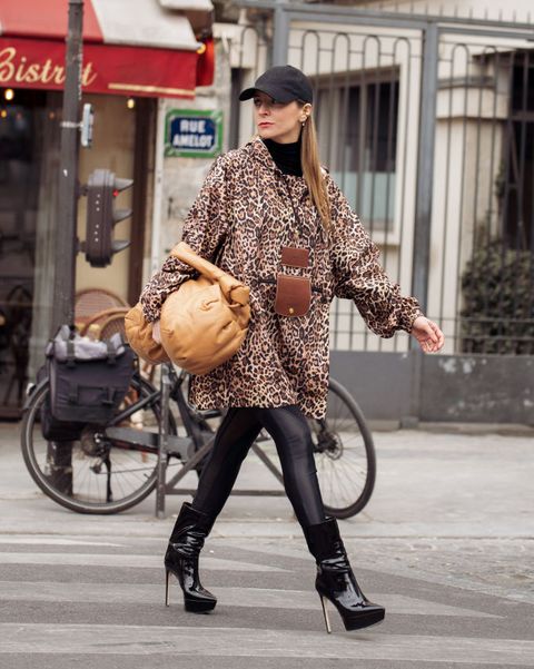 vrouw in panterblouse met legging en hoge laarzen loopt op straat tijdens paris fashioni week