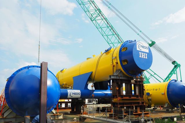 kairyu deep sea turbine in yellow and blue with a green crane in the background on a sunny day with blue skies