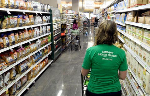 Kaitlin Myers a shopper for Instacart studies her smart phone as she  shops for a customer at Whole Foods in Denver.