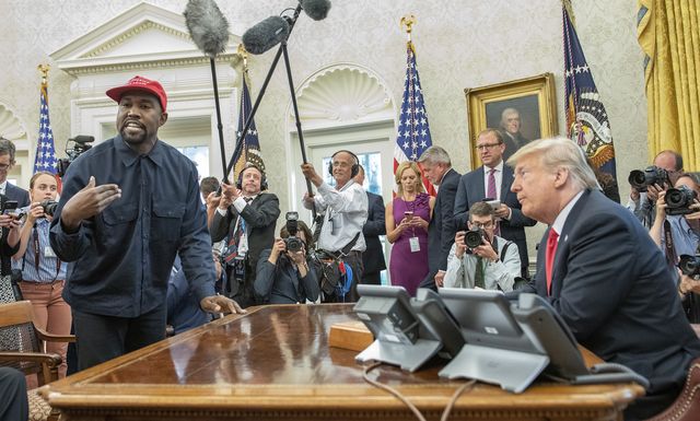 surrounded by members of the press and others, american rapper and producer kanye west stands as he talks with real estate developer and us president donald trump in the white house's oval office, washington dc, october 11, 2018 west wears a red baseball cap that reads 'make america great again,' trump's campaign slogan photo by ron sachsconsolidated news picturesgetty images