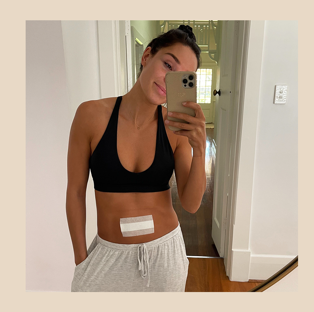 kayla itsines taking a selfie in a sports bra with a bandage on her stomach