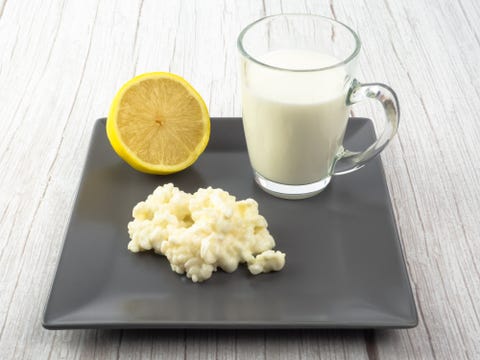 kefir fungus and whole cow's milk in a glass cup and half lemon