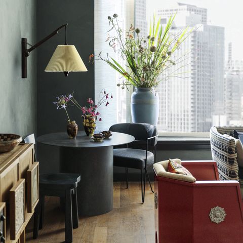 proper los angeles, properhotelcom hotel room with wooden plank floors a red moroccan low seat and a black round pedestal table and chairs with large urn with flowers by the window