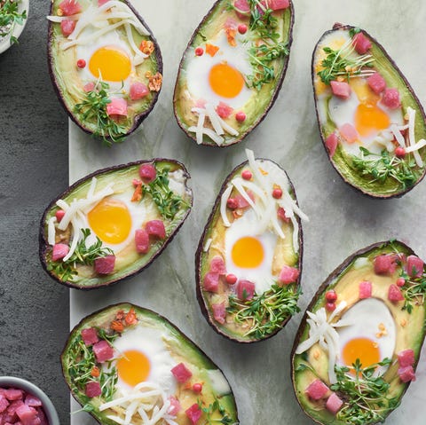 Keto diet dish: Avocado boats with ham cubes, quail eggs, cheese and cress sprouts keto diet dish avocado boats with ham cubes, quail eggs, cheese and cress sprouts on stone serving board