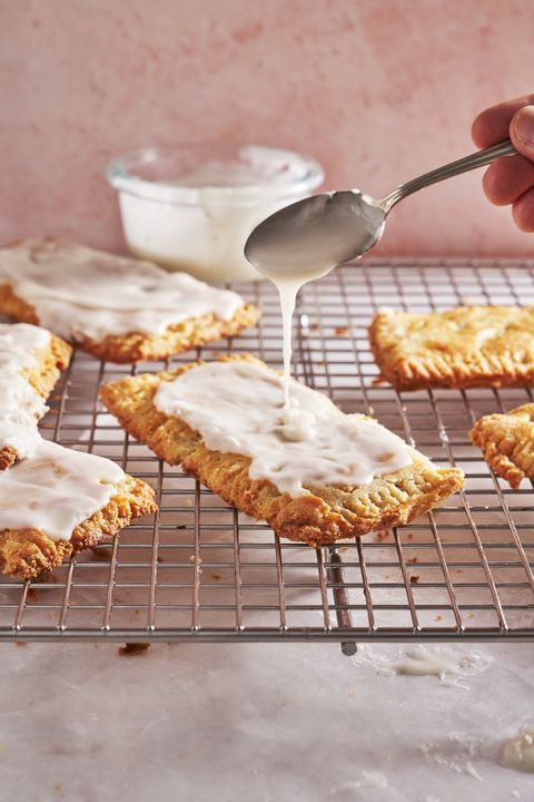 icing being drizzled onto a tray of gluten free pop tarts
