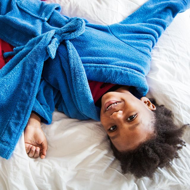 kid lying on bed in blue bathrobe