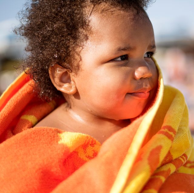 baby wrapped in orange and yellow beach towel