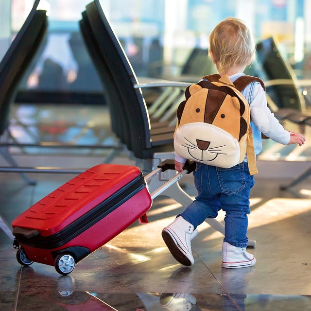 toddler with lion backpack rolling red kids suitcase in airport