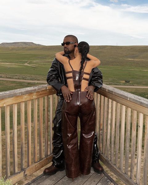 kim kardashian wears a brown patent leather jumpsuit or tank and trouser set standing next to kanye west at a ranch on instagram