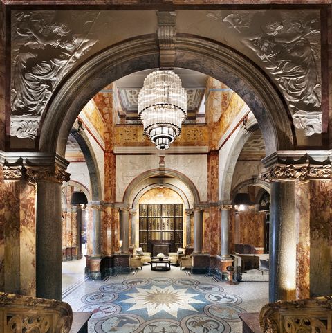 Ornate hotel lobby with pillars, tiled floor and giant chandelier