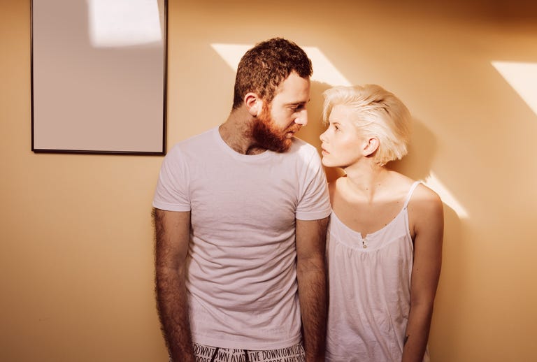 Portrait of young couple in living room looking each other.