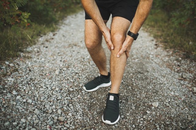 knee injury on running outdoors man holding knee by hands closeup and suffering with pain sprain ligament or meniscus problem
