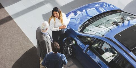 high angle view of saleswoman showing car to customers at showroom