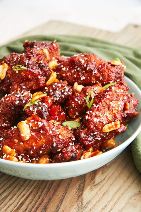 bowl of korean fried chicken garnished with sesame seeds, scallions, and peanuts