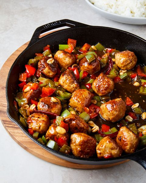 kung pao meatballs with red and green peppers and peanuts in a black cast iron pan