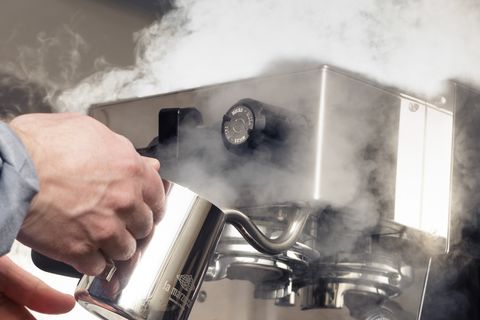 a person making steamed milk with an espresso machine